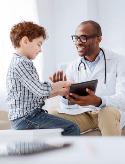 A pediatrician showing a young patient medical records on a tablet, demonstrating how to safely fax medical records using secure technology.