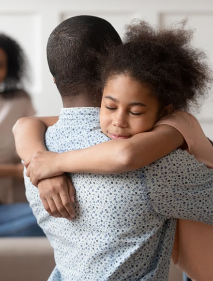 Young girl embracing her father, symbolizing the support offered by behavioral healthcare services.