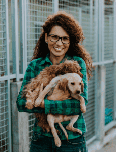 Smiling volunteer at an animal shelter holding a rescued dog, depicting the community and care in nonprofits that can benefit from cloud fax solutions.